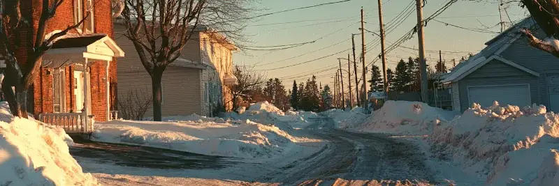 La même rue en fin d’après-midi, lumière dorée rasante sur la neige et la chaussée dégagée